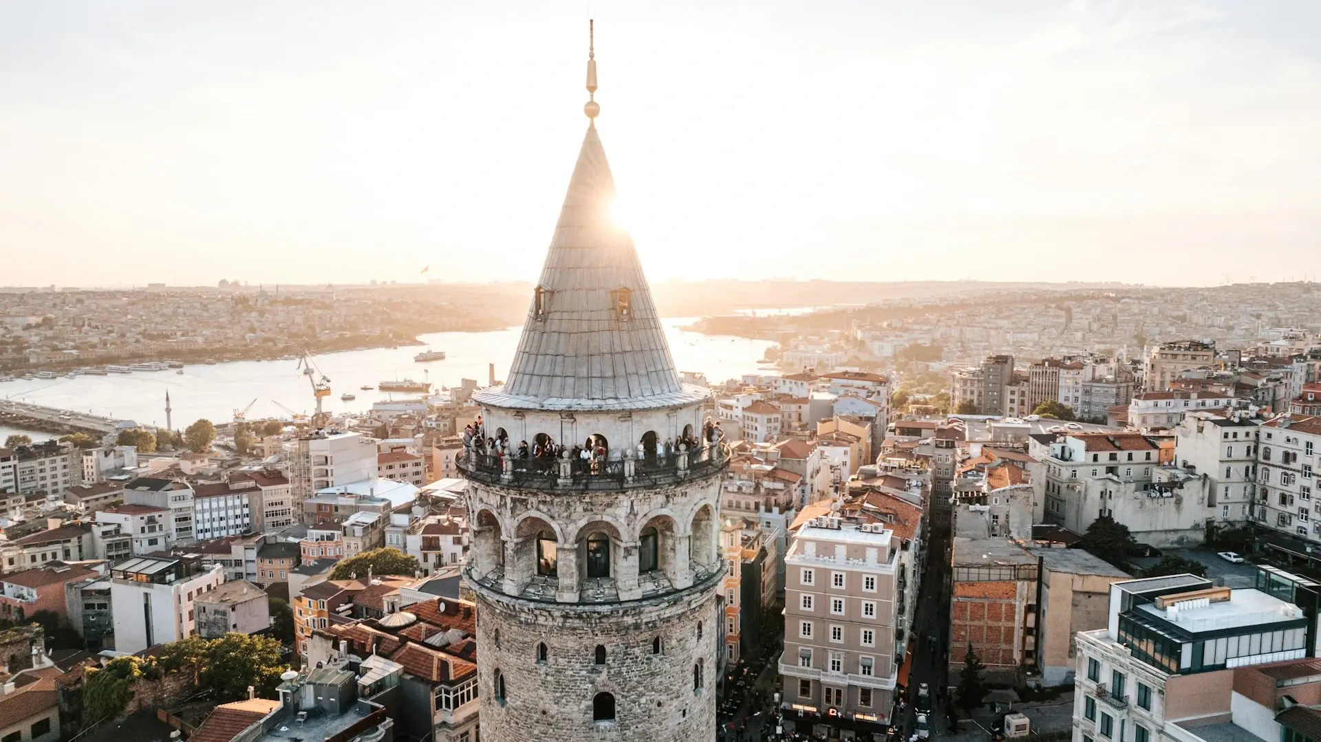 Galatatoren in Istanbul bij zonsondergang, met de Gouden Hoorn en de skyline van de stad op de achtergrond.