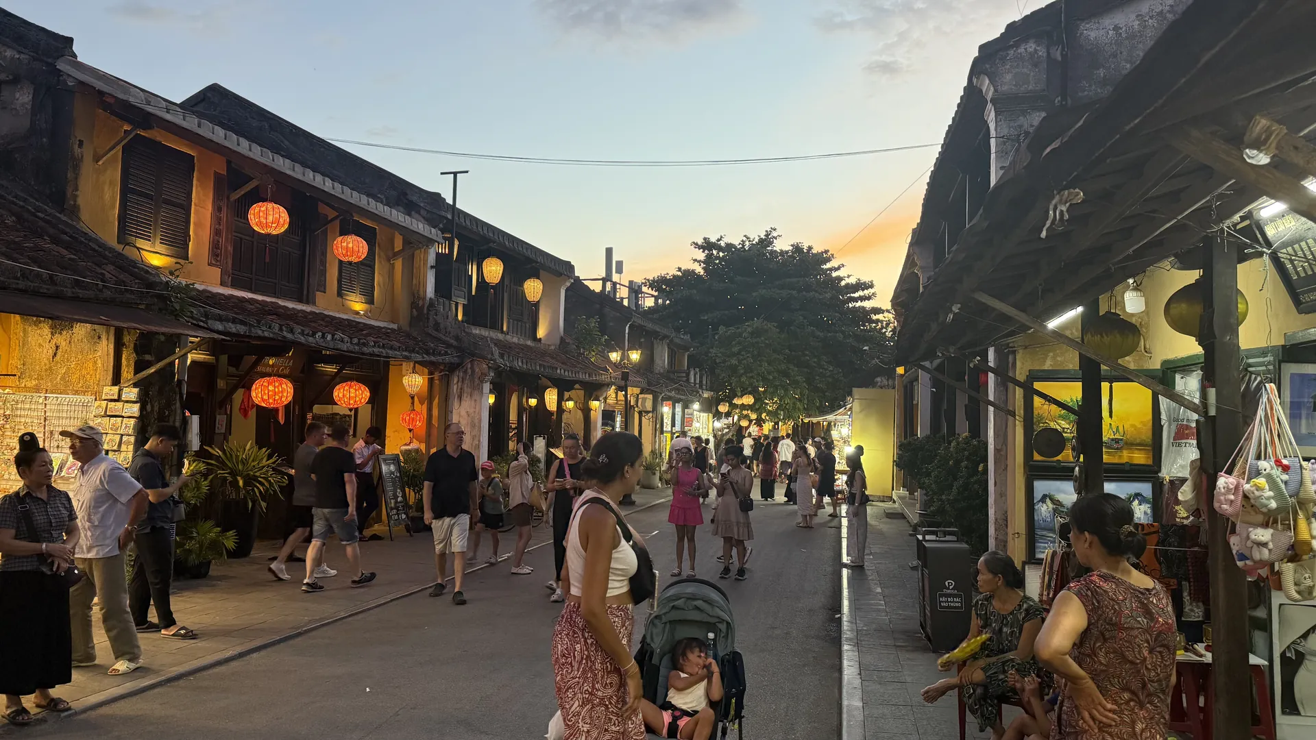 De oude binnenstad van Hoi An in de schemering, met brandende zijden lampionnen langs de houten winkelpuien en wandelende mensen in de voetgangersstraat