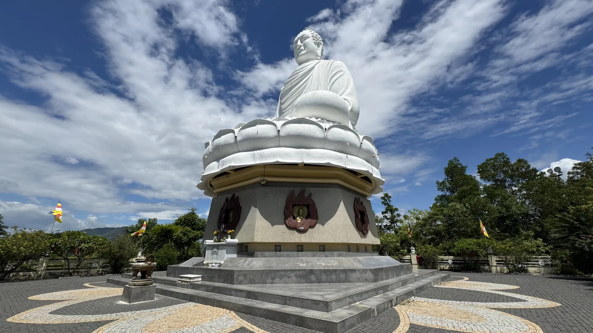 De witte Kim Than Phat To-Boeddha op een lotustroon bij de Long Son-pagode in Nha Trang, gezien vanaf het mozaïekplein eronder tegen een blauwe lucht